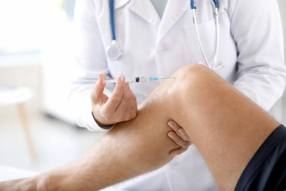 "Patient receiving joint injection from a medical professional for pain relief."