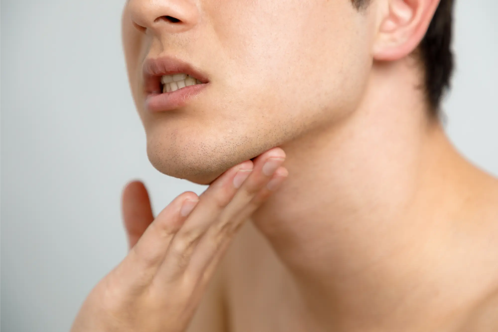 Side view of a person gently touching their jaw, illustrating Botox treatment for TMJ-related muscle tension.