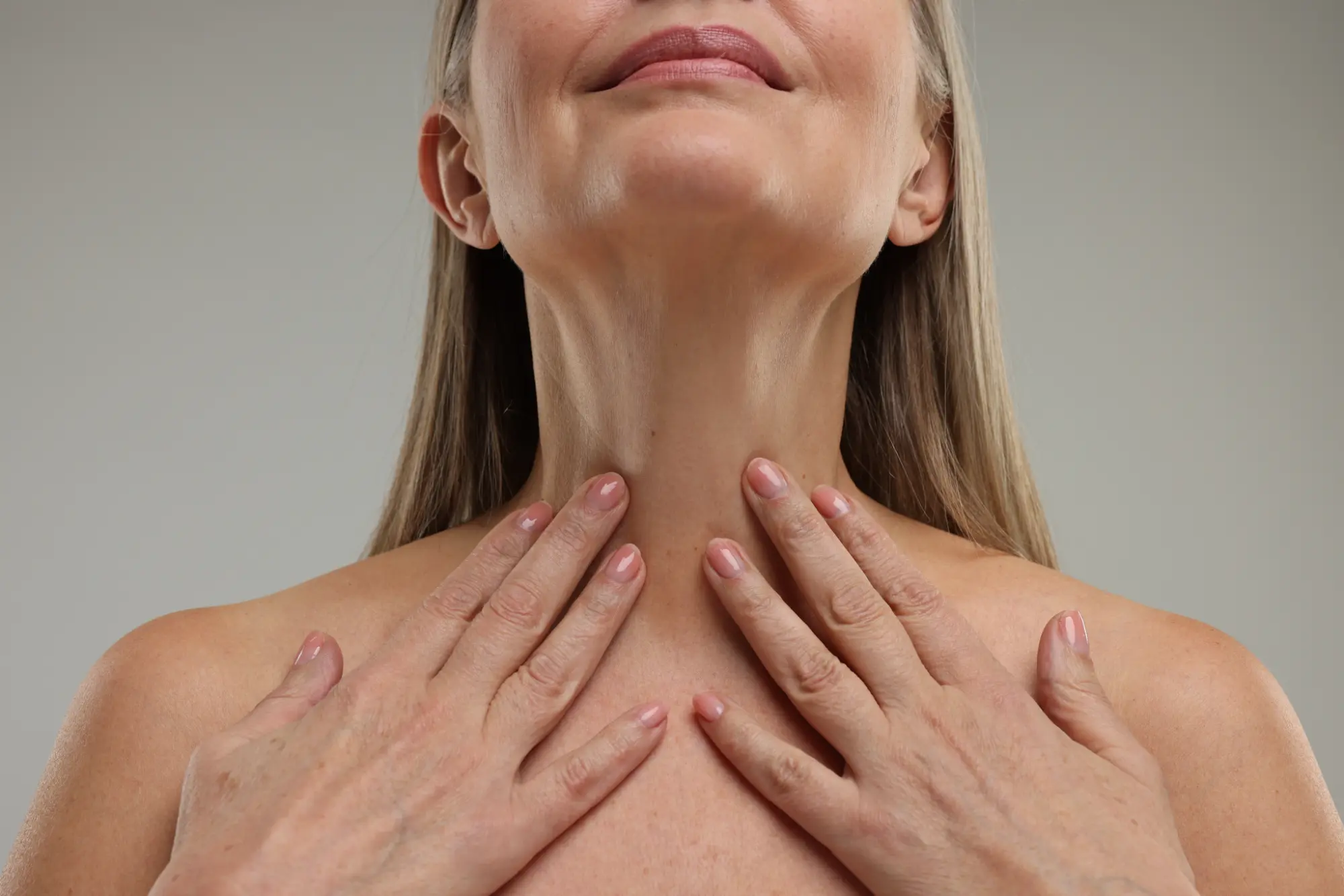 Hands touching neck to highlight wrinkle relaxer treatment area.