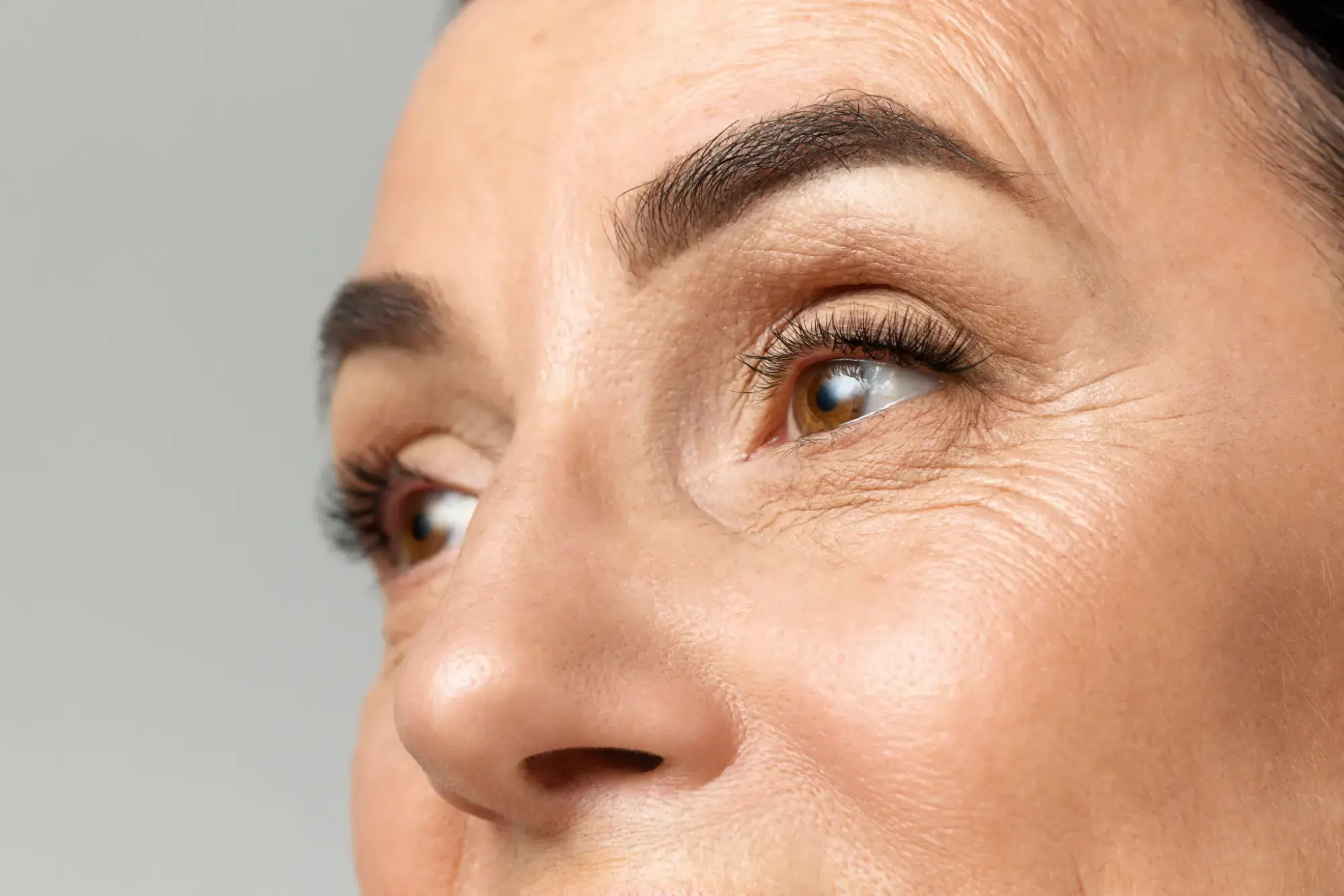 Woman smiling and touching her cheek, illustrating Botox wrinkle relaxer treatment cost and waiting information.