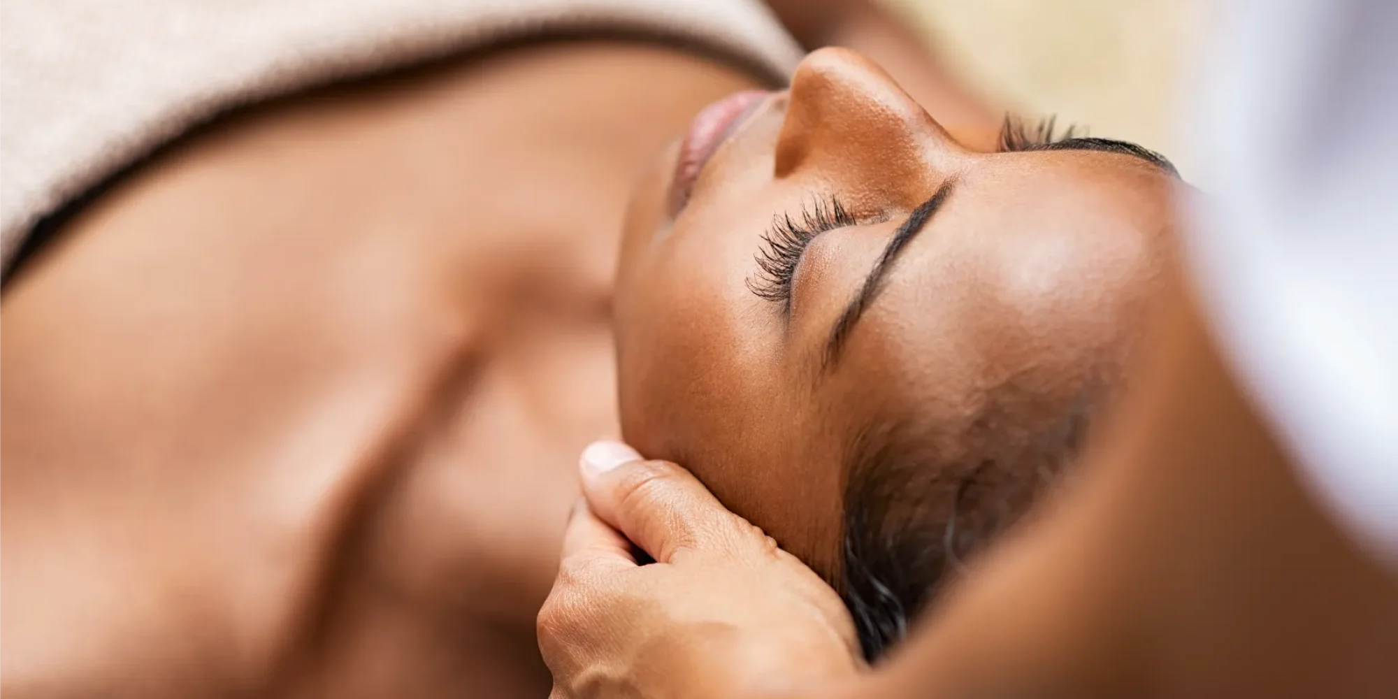 “Person lying on a massage table receiving a head and neck massage from a therapist.”